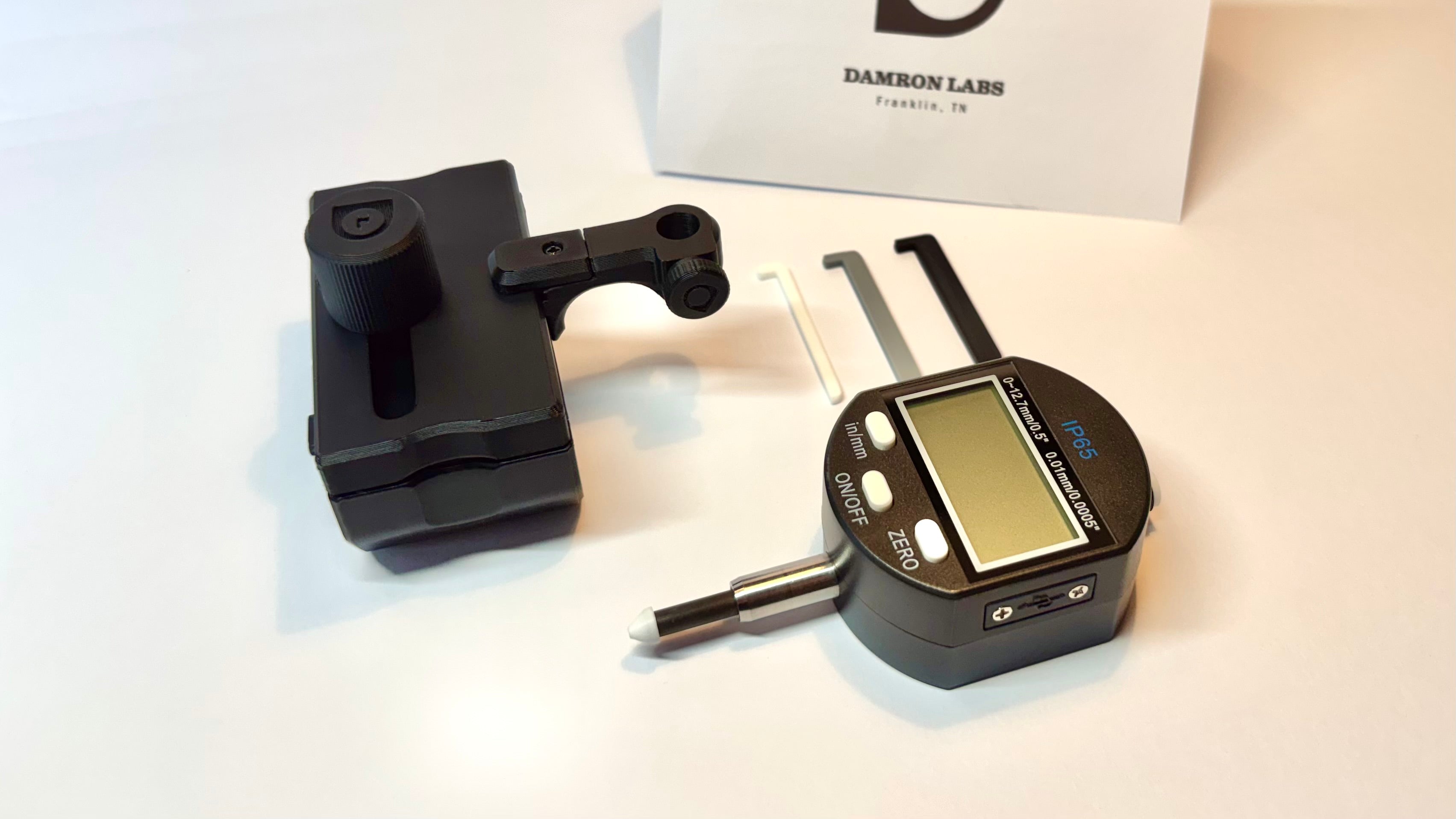 Digital caliper and DL Action Finder on a white background with a box labeled 'Damron Labs